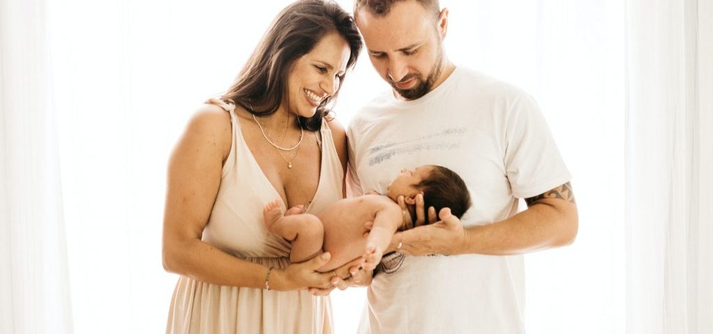 Photo montrant un jeune couple heureux, tenant un nourrisson.