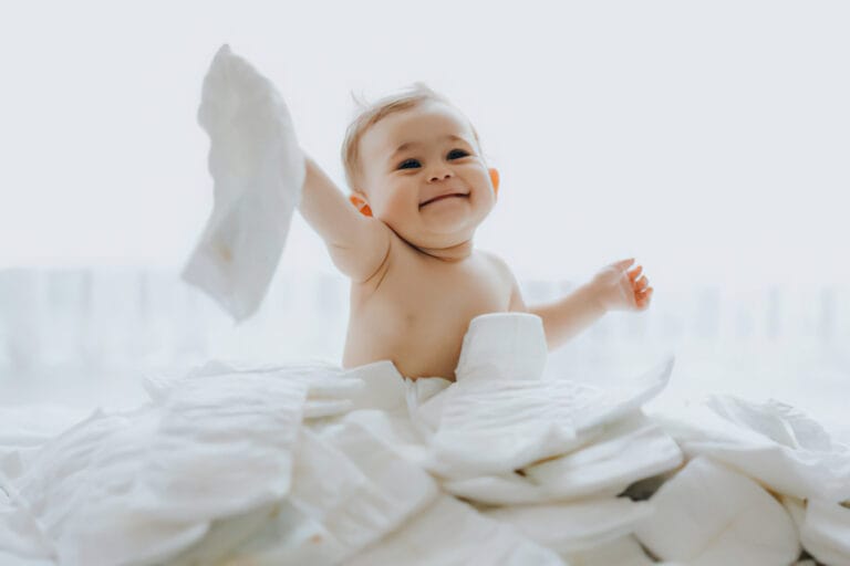 Photo montrant un bébé souriant au milieu d'une pile de langes.